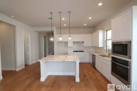 A kitchen with white cabinets and a wooden floor.