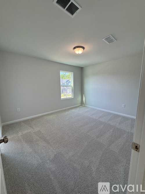 A room with a carpeted floor and a window showing a view of a building outside.