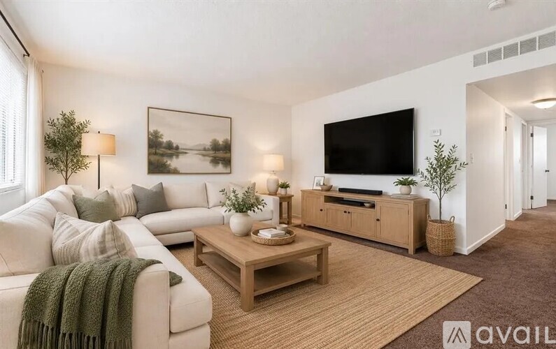A living room with a white couch, a wooden coffee table, and a large flat-screen TV mounted on the wall.