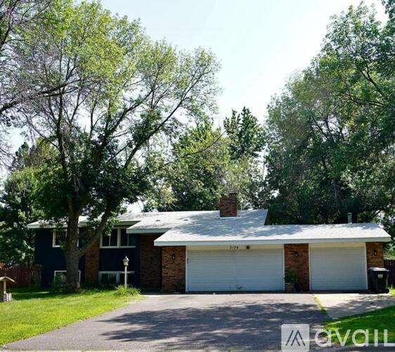A house with a white garage door is surrounded by trees.