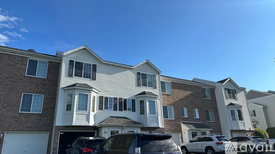 A row of houses with cars parked in front.