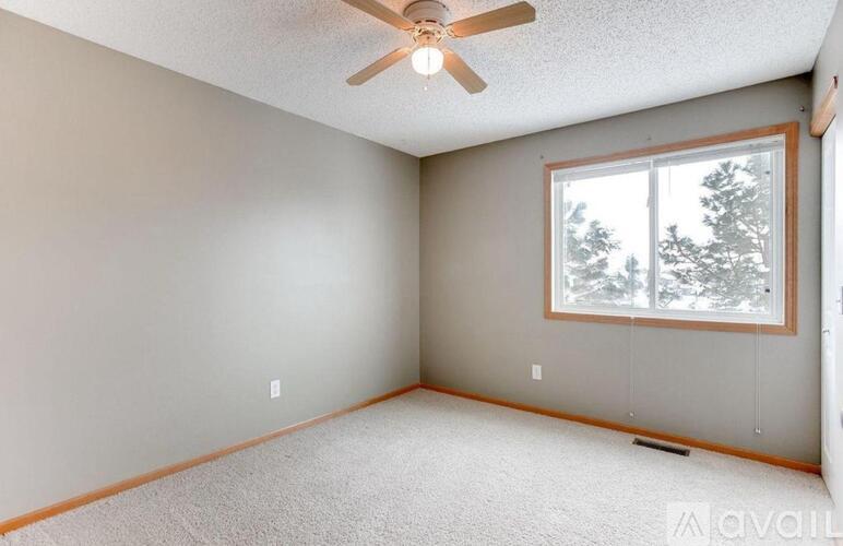 A room with a ceiling fan and a window showing trees outside.