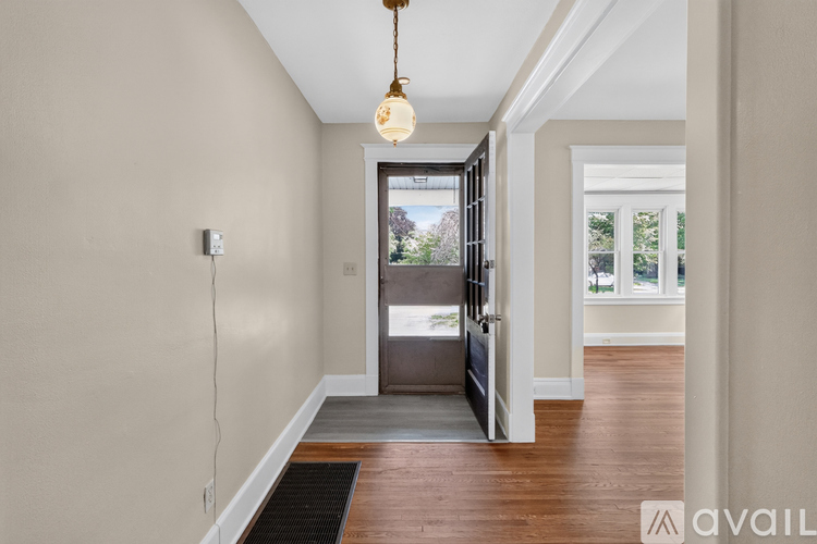 A hallway with a wooden floor and a brown rug.