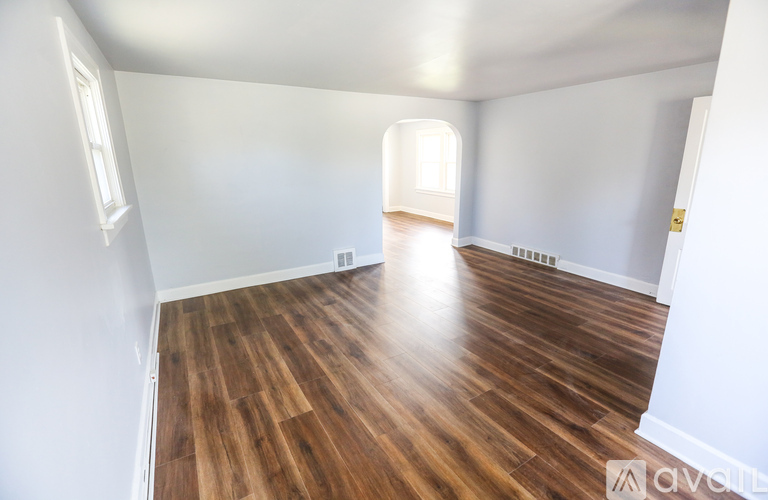 A room with wooden flooring and white walls.
