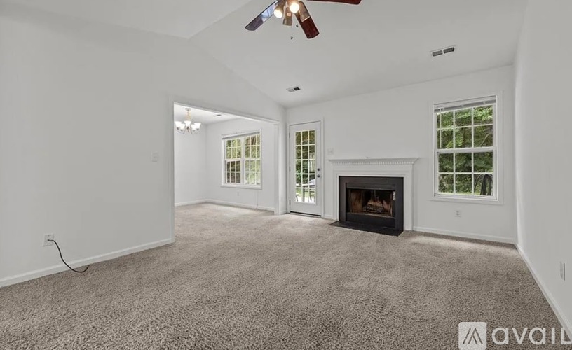 A spacious living room with a fireplace and a ceiling fan.