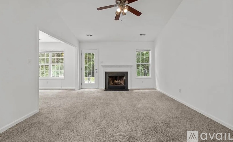A spacious living room with a fireplace and a ceiling fan.