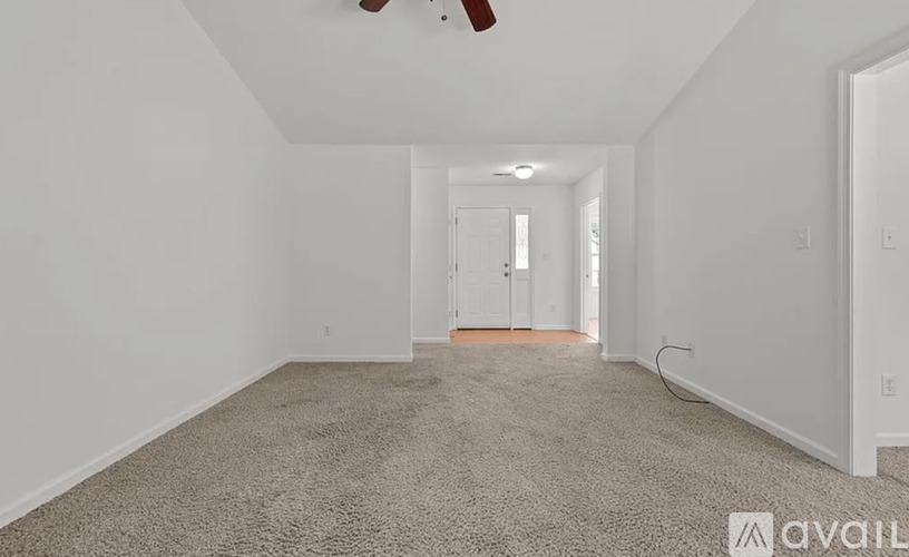A spacious room with a carpeted floor and a ceiling fan.