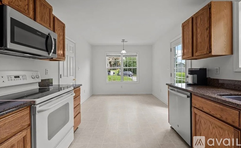A kitchen with wooden cabinets and white appliances is available for rent.