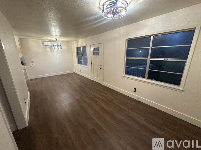 A room with wooden flooring and a window with a view of the night sky.