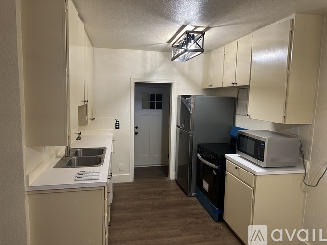 A kitchen with white cabinets and a black fridge.