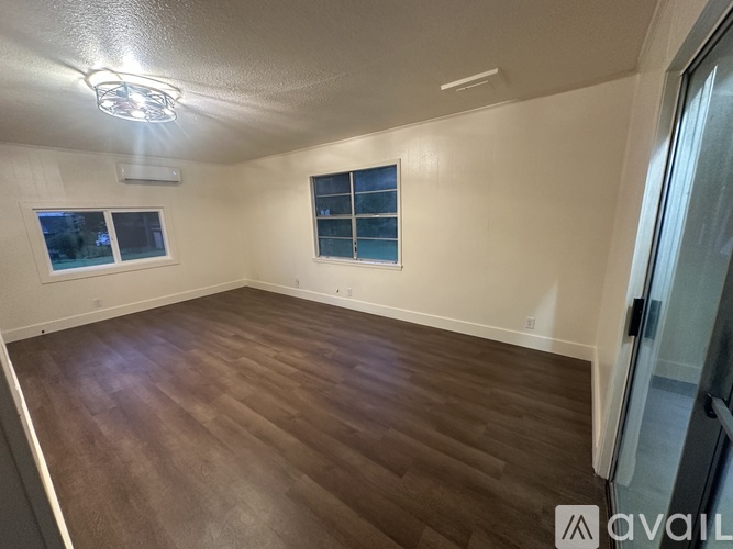 A room with wooden flooring and a window with a view of the sky.