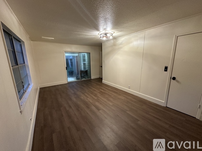 A room with wooden flooring and a door leading to another room.
