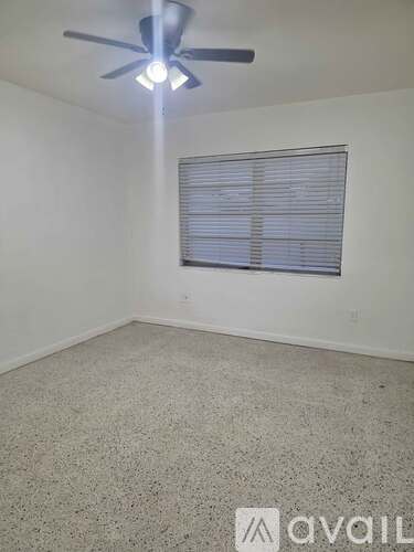 A room with a ceiling fan and a window with blinds.