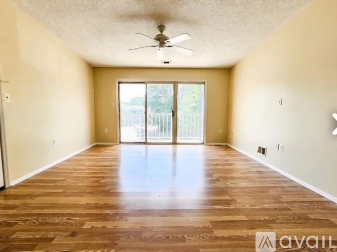 A spacious room with wooden flooring and a ceiling fan.