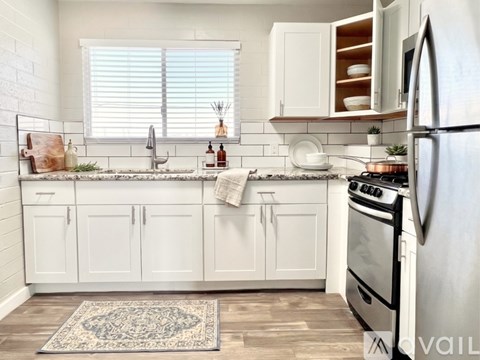 A kitchen with white cabinets and a black fridge.