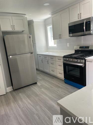 A kitchen with a stainless steel refrigerator and a black stove top oven.