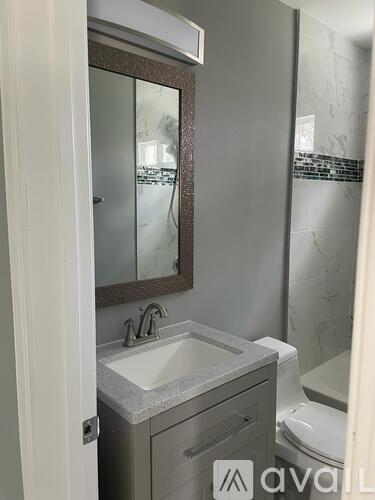 A bathroom with a sink, mirror, and toilet.