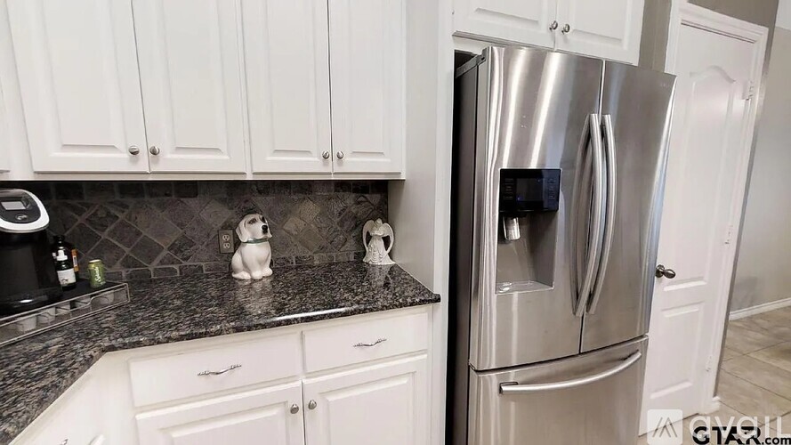 A kitchen with white cabinets and a stainless steel refrigerator.