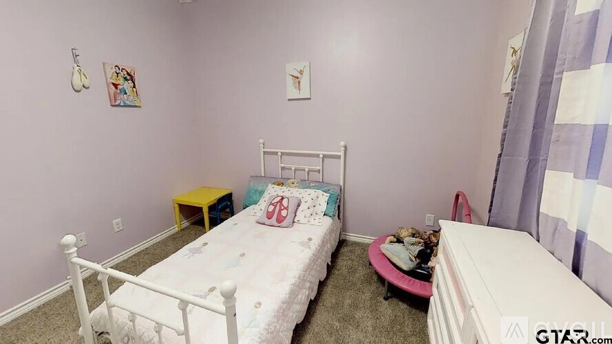 A small bedroom with a white bed and a pink ottoman.
