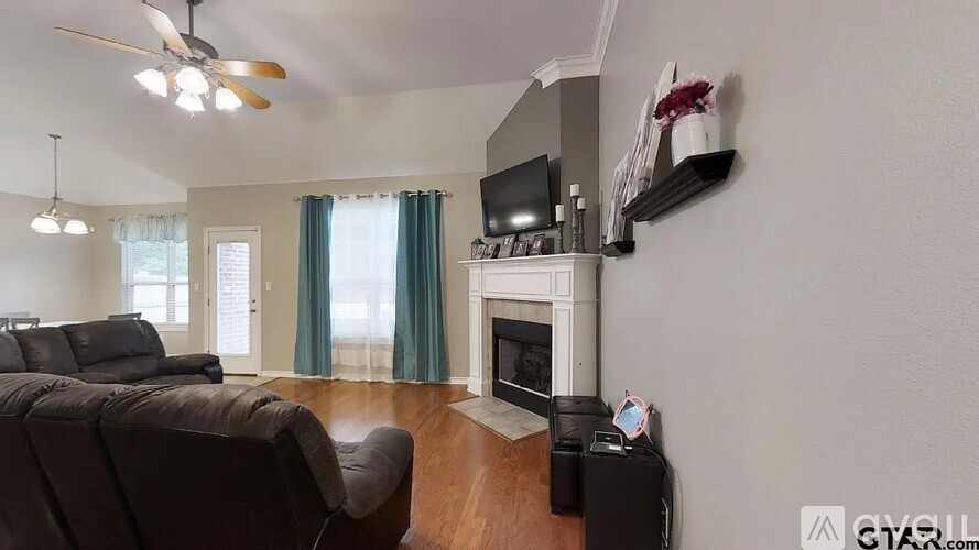 A living room with a grey couch and a white fireplace.