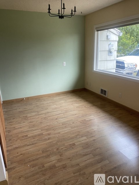 A room with wooden flooring and a window overlooking a street.