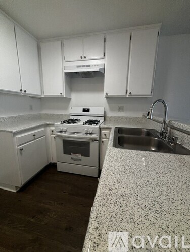 A kitchen with white cabinets and a granite countertop.
