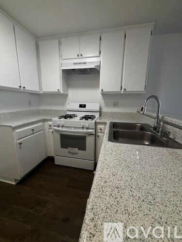A kitchen with white cabinets and a granite countertop.