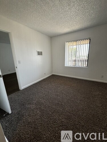 A room with a carpeted floor and a window with blinds.