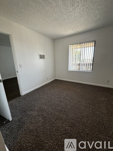 A room with a carpeted floor and a window with blinds.