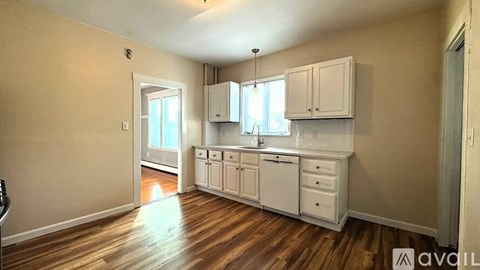 A kitchen with white cabinets and a wooden floor.