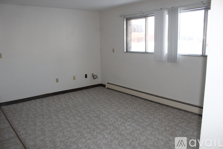 A room with a carpeted floor and a window with white curtains.