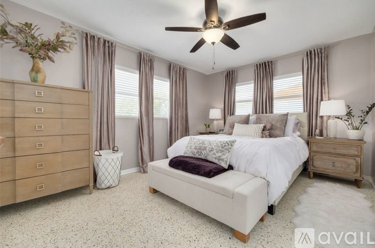 A bedroom with a large bed, a dresser, and a ceiling fan.