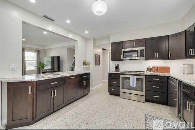 A modern kitchen with dark wood cabinets and stainless steel appliances.