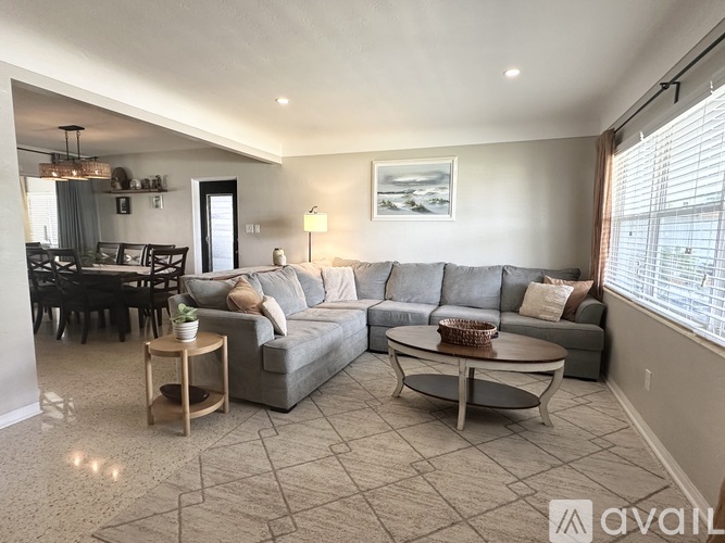 A living room with a grey couch, a coffee table, and a dining table with chairs.