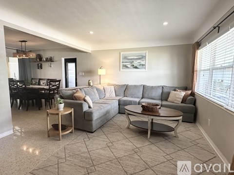 A living room with a grey couch, a coffee table, and a dining table with chairs.