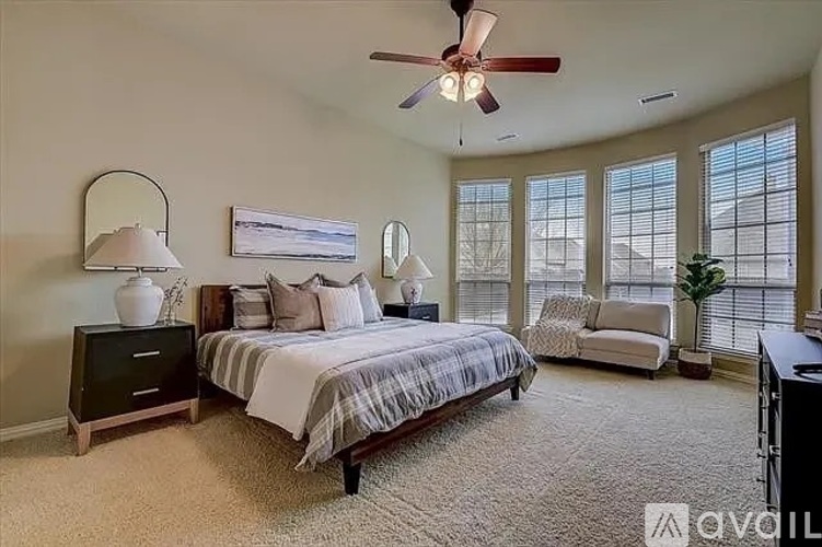 A bedroom with a bed, a chair, and a ceiling fan.