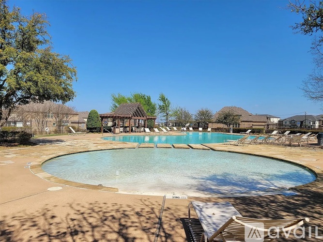 A large outdoor swimming pool surrounded by trees and lounge chairs.