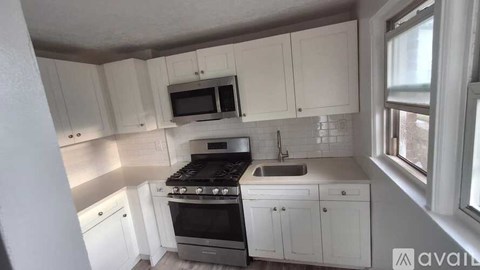 A kitchen with white cabinets and a black stove top.