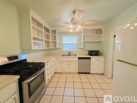 A kitchen with white cabinets and a black stove top oven.