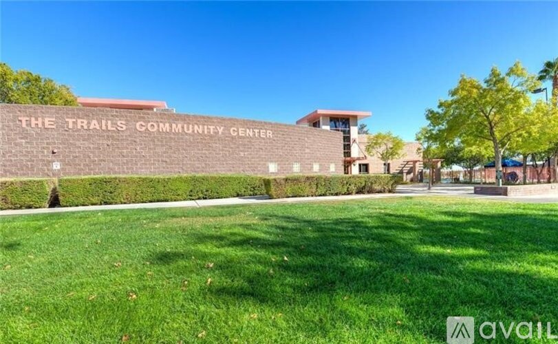 The Trails Community Center is a large building with a red roof and a green lawn in front.