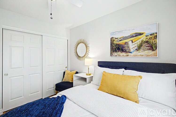 A bedroom with a white bed and a yellow pillow.