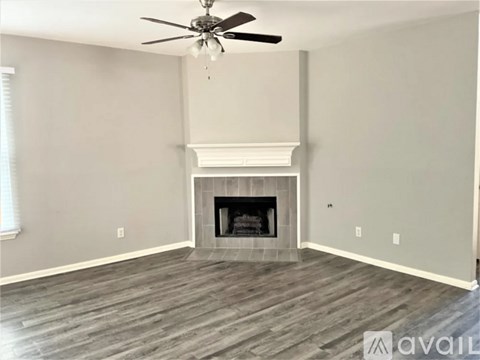 A living room with a fireplace and a ceiling fan.