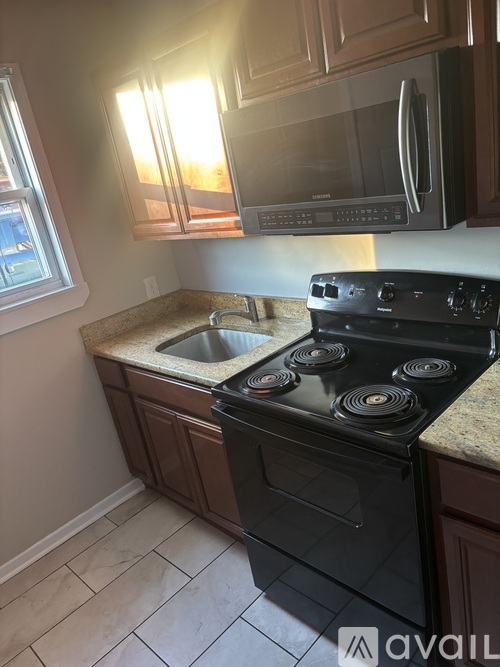 A kitchen with a black stove top oven and microwave above it.