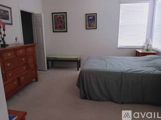 A bedroom with a bed, dresser, and window.