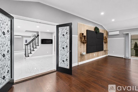 A modern living room with a wooden floor and a black television mounted on the wall.