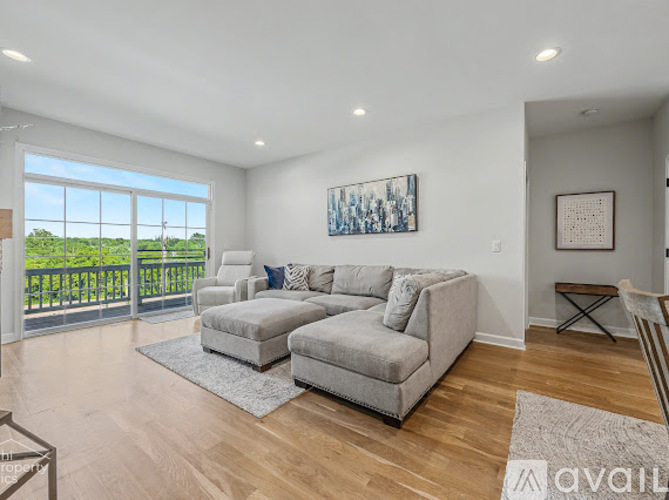 A living room with a grey couch and a painting on the wall.