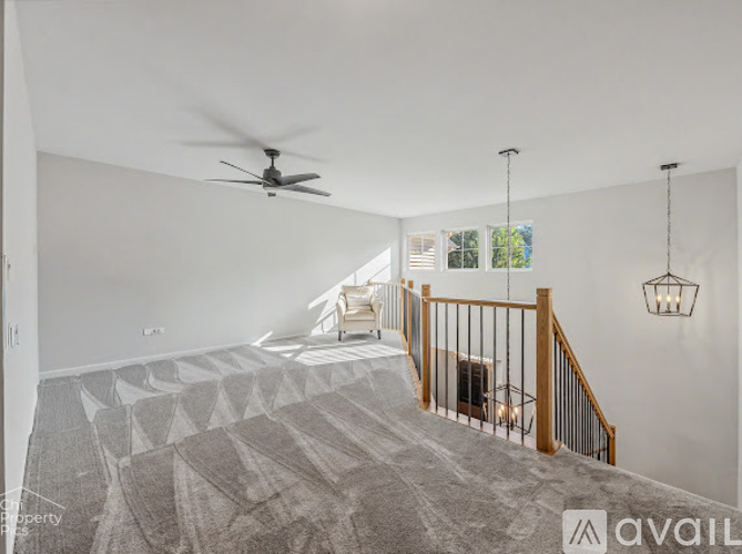 A spacious room with a staircase and a ceiling fan.