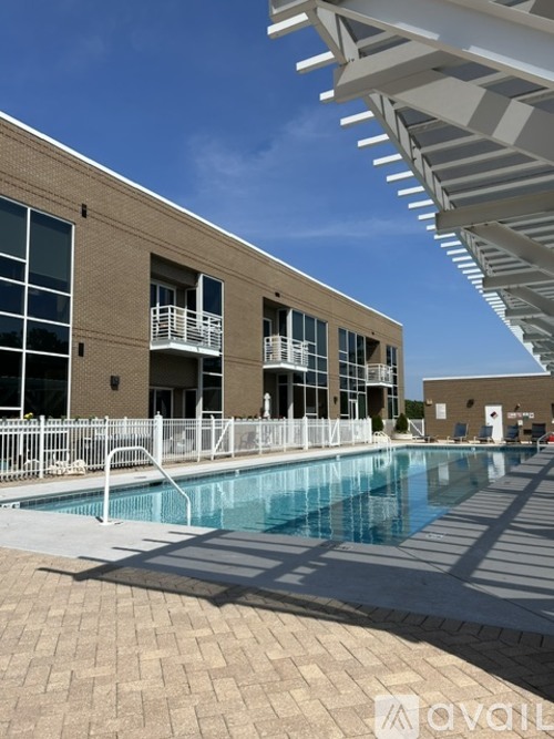A large swimming pool in front of a building with a white pergola over it.