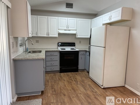 A kitchen with white cabinets and a white refrigerator.