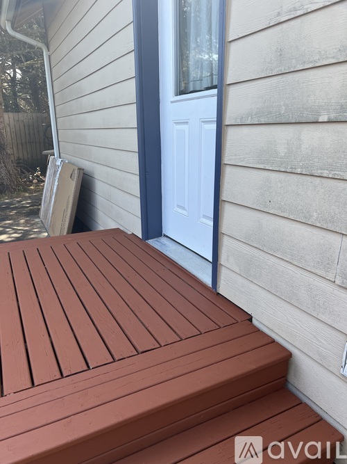 A wooden deck with a red table and a blue door.